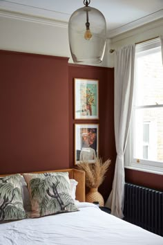 a bedroom with red walls and pictures on the wall