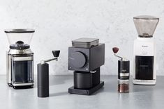 three different types of coffee makers on a counter top, one is silver and the other is black