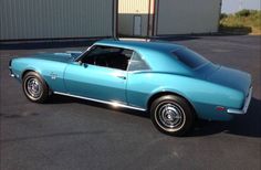 a blue muscle car parked in a parking lot