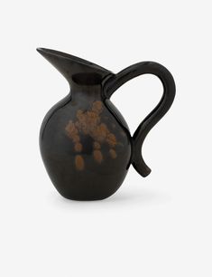 a black and brown vase sitting on top of a white table