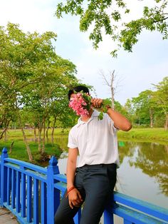 a man sitting on a blue bridge with flowers in his mouth