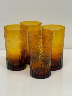 four yellow glasses sitting next to each other on a table