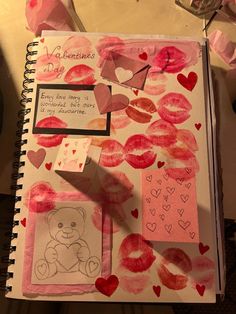 an open notebook with pink and red watercolors on it next to a teddy bear