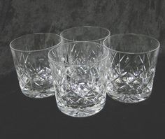 four clear glass tumblers on a black background