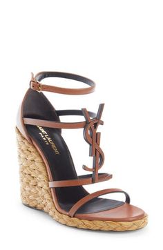 A tonal YSL logo dominates the front of this strappy calfskin sandal given a vacay-ready update with a braided-raffia wedge. 4" (105mm) heel; 1/2" platform (size 37) Adjustable ankle strap with buckle closure Leather/synthetic upper, leather lining and leather/synthetic sole Made in Italy Women's Designer Shoes Ysl Heels, Ysl Logo, Girly Shoes, Casual Heels, Fabulous Shoes, Footwear Design Women, Handbag Shoes, Shoe Obsession, Wedge Sandal