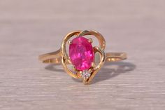 This stunning piece, known as The Heart's Embrace, features a captivating 1.08 carat oval brilliant cut ruby at its center. The vibrant ruby is elegantly set in a heart shaped Fibonacci motif crafted from 14 karat yellow gold, adding a touch of romantic sophistication. Accentuating the center stone is a single natural diamond, enhancing the ring's overall brilliance. The ring is currently a finger size 6.75. The Heart, Ruby And Diamond Ring, Rings Statement, A Heart, Halloween Shopping, Natural Diamonds, Statement Rings, Heart Shapes, Diamond Ring