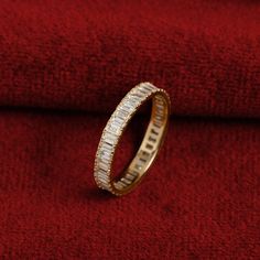 a gold ring with baguettes and diamonds on red velvet background, close up