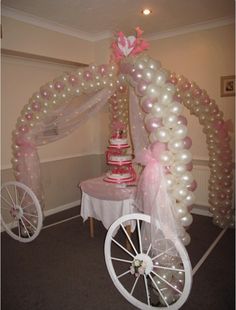 a wedding cake and balloon arch in the shape of a horse drawn carriage