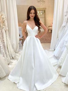 a woman in a white wedding dress standing next to dresses on mannequins