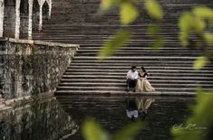 a man and woman are sitting on the steps in front of some water with their arms around each other