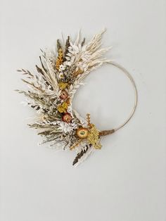 a white headband with dried flowers and leaves on it, against a white background