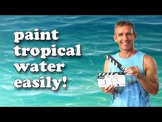 a man holding a clapstick in front of the ocean with words paint tropical water easily