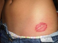 a woman's stomach with a red lipstick imprint on it and a tag around her waist