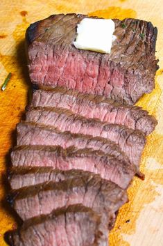 sliced steak with butter on top sitting on a cutting board