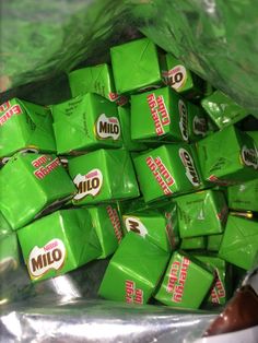 a bag filled with green candy bars sitting on top of a table next to a pile of chocolates