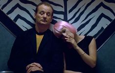 a man and woman sitting next to each other in front of a zebra print wall