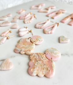 pink and white earrings laying on top of a table next to other pieces of jewelry