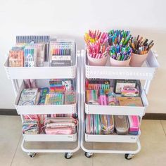 two white bins filled with different types of stationery and pencils on wheels