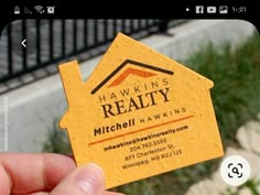 a person holding up a business card that says hawkins realty mitchell hawkins