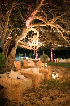 an outdoor seating area with hay bales and candles lit up in the night sky