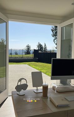 a desk with a computer on top of it in front of a sliding glass door