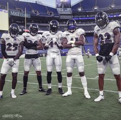 three football players are standing on the field with their hands in each other's pockets