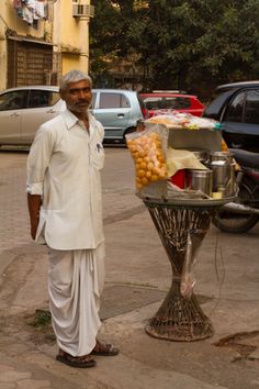 a man standing next to a table full of food on the side of a road