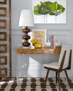 a room with a desk, lamp and pictures on the wall above it that is decorated in brown and white