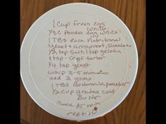 a white plate with writing on it sitting on top of a wooden table next to a wall