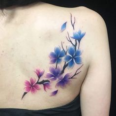 a woman's back with flowers painted on her shoulder and the upper part of her body