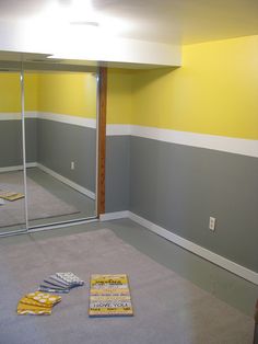 an empty room with yellow and gray paint on the walls, carpeted floor and mirror doors