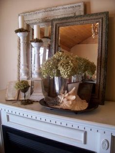 a fireplace mantel topped with a mirror and vase filled with flowers on top of it