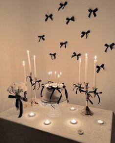 a table topped with a cake covered in black ribbon and lit candles next to it