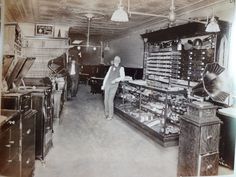 an old black and white photo of a woman in a room with many items on display