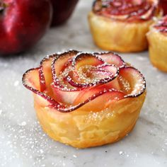 some food that is on a table with apples in the background and powdered sugar