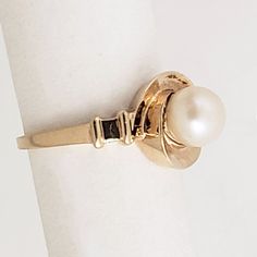 "A whirl of a pearl ring! This vintage 14K gold ring has a design that makes it distinctive without losing its classic look. The cultured pearl has nice, consistent color and is centered in a hurricane style setting. Stepped shoulders add another unique twist to this ring which is in wonderful condition. Vintage: 1960s - 1980s Size: 6 1/2 Materials: 14K Yellow Gold, Cultured Pearl Marked: 14K Pearl: 6.7mm diameter Width North to South: 7/16\" Width East to West: 3/4\" Stands Off Finger: 5/16\" S Classic 14k Gold Bypass Ring For Formal Occasions, Classic White Bypass Ring For Formal Occasions, Classic Round Rings With Pearl Drop, Classic Pearl Solitaire Rings, Classic Oval Akoya Pearl Ring, Classic Pearl Drop Ring, Classic Solitaire Pearl Rings, Classic Solitaire Bypass Ring For Formal Occasions, Classic Solitaire Bypass Ring For Formal Events