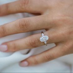 a close up of a person's hand with a diamond ring on their finger