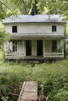 an old white house sitting in the woods