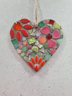 a heart shaped glass ornament hanging on a rope