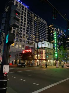 a traffic light sitting on the side of a road next to tall buildings at night