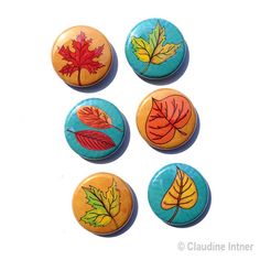 four buttons with leaves painted on them in different colors and sizes, sitting next to each other