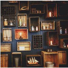 several wooden crates are stacked on the wall with bottles and jars in them, along with other items