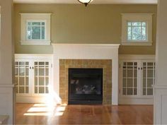 an empty living room with a fireplace and windows