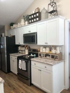 a kitchen with white cabinets and black appliances