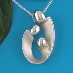 "Mother of two children pendant may also be interpreted as celebrating your family of three! Our expressive, egg-shaped creation is hand sculpted in sterling silver. Size: 1\" X 3/4\": $145. Bright polished heads and raised curves are contrasted with recessed contours that have a soft satin finish. Fully finished reverse. This dimensional pendant includes a sterling chain that threads through the design's integrated and invisible chain bail. The included US-made 1.2mm curb link chain with spring Hand Cast Pendant Jewelry For Anniversary, Oval Sterling Silver Hand Cast Jewelry, Sterling Silver Oval Necklace For Mom, Oval Sterling Silver Necklace For Mom, Sterling Silver Oval Pendant Necklace As Gift For Mom, Hand Cast Oval Pendant Jewelry Gift, Silver Oval Pendant Jewelry For Mom, Sterling Silver Necklace With Polished Finish For Mother's Day, Silver Oval Pendant Jewelry Gift For Mom