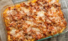 a casserole dish with meat and cheese in a glass baking dish on a wooden table