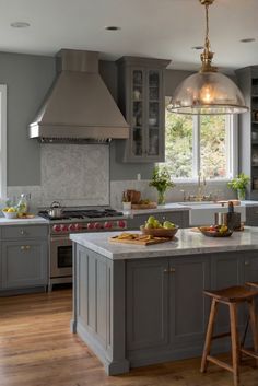 a kitchen with gray cabinets and an island in the middle is lit by two pendant lights