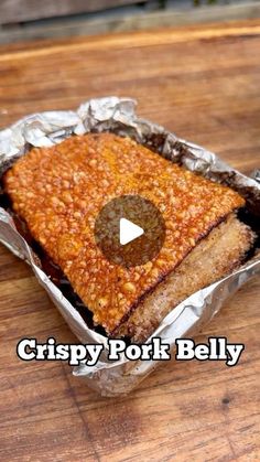 crispy pork belly in tin foil on top of a wooden table with the words crispy pork belly