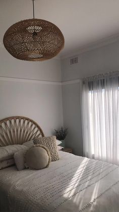 a bed with white sheets and pillows in a bedroom next to a curtained window