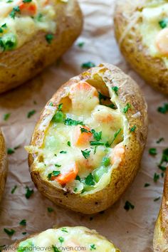 baked potatoes with shrimp and cheese in them on a piece of parchment paper, ready to be eaten